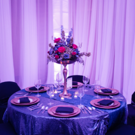 mostly purple image, a well decorated table with a floral center piece and gold plates. 